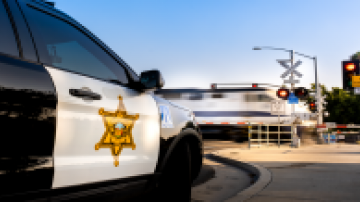 Orange County police vehicle waiting for a train to pass